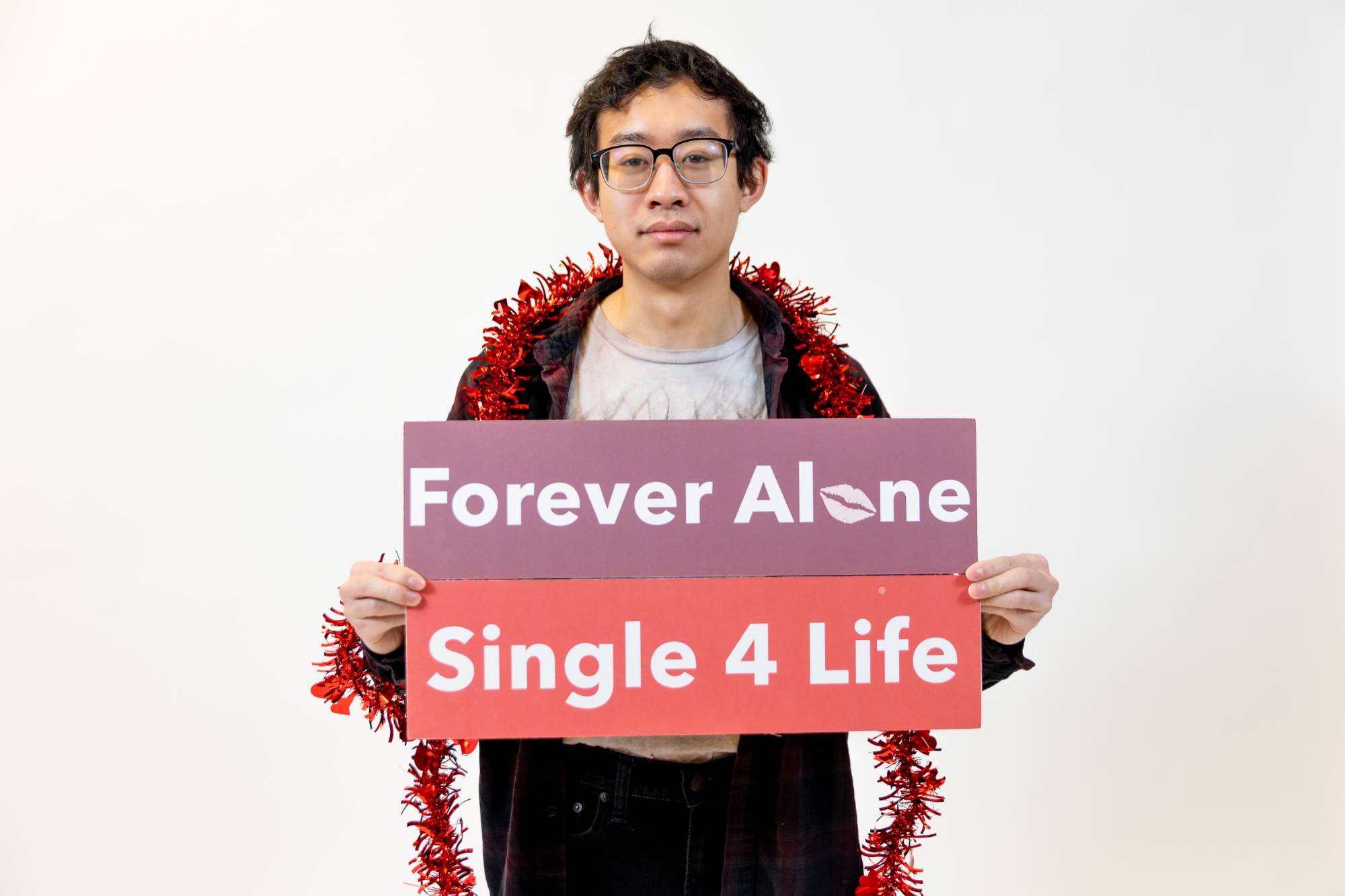 Student holding "forever alone" signs at Valentine's day photoshoot